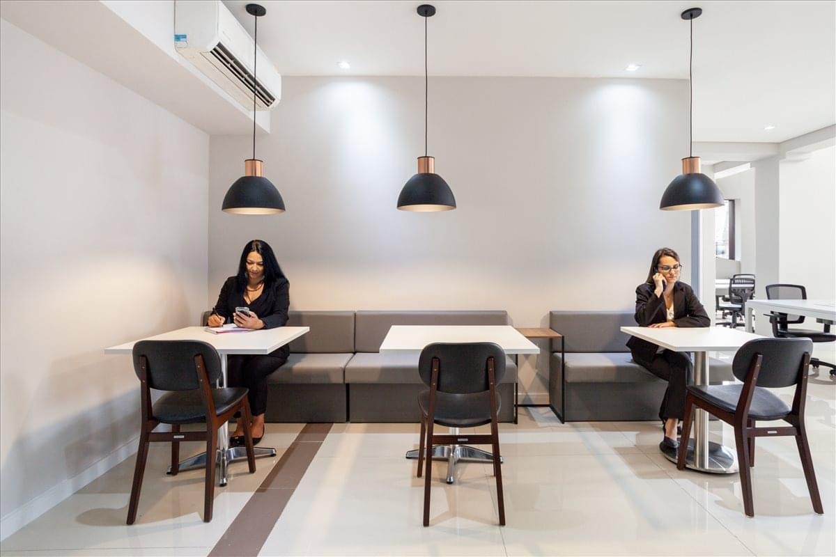 Communal breakout area featuring cafe-style seating and modern pendant lighting at Avenida dos Autonomistas 2561.