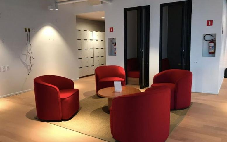 Modern reception area at Market Place featuring four red tub chairs around a circular wood table.
