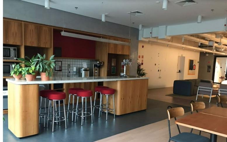 Kitchen and dining area at Market Place with a wooden breakfast bar, red stools, and potted plants.