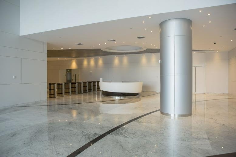 Spacious modern lobby at Lima Central Tower featuring a curved white reception desk and polished floors.