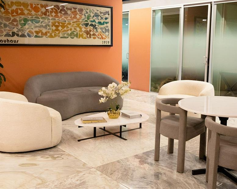 Reception area featuring orange walls, curved grey sofa, and marble floors.