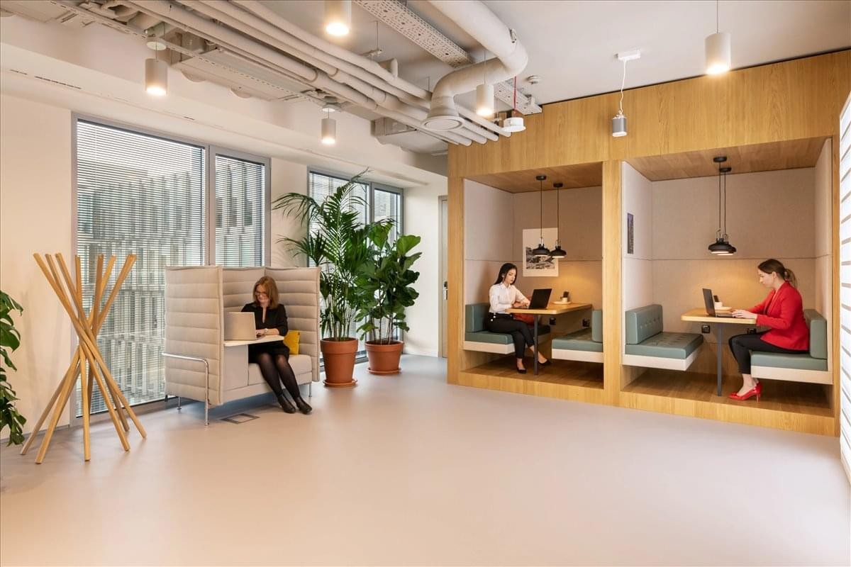 Spacious communal lounge at 1877 Avenida Revolucion featuring private wooden work booths and indoor plants.