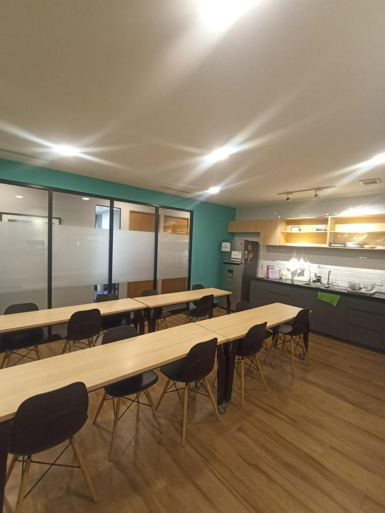 Bright coworking area at Belisario Domínguez 2020 with long wooden tables and a teal accent wall.