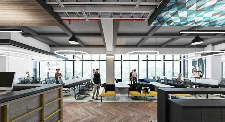 Wide-angle open-plan workspace with industrial ceilings, yellow seating, and large windows.