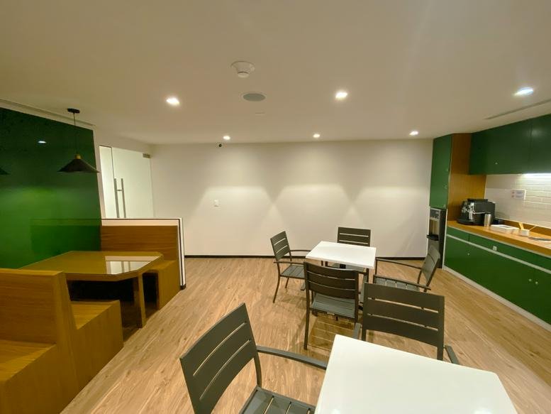 Communal dining area at Bosques de Ciruelos 186, Pisos 10-A y 12 with green accents and wooden booths.