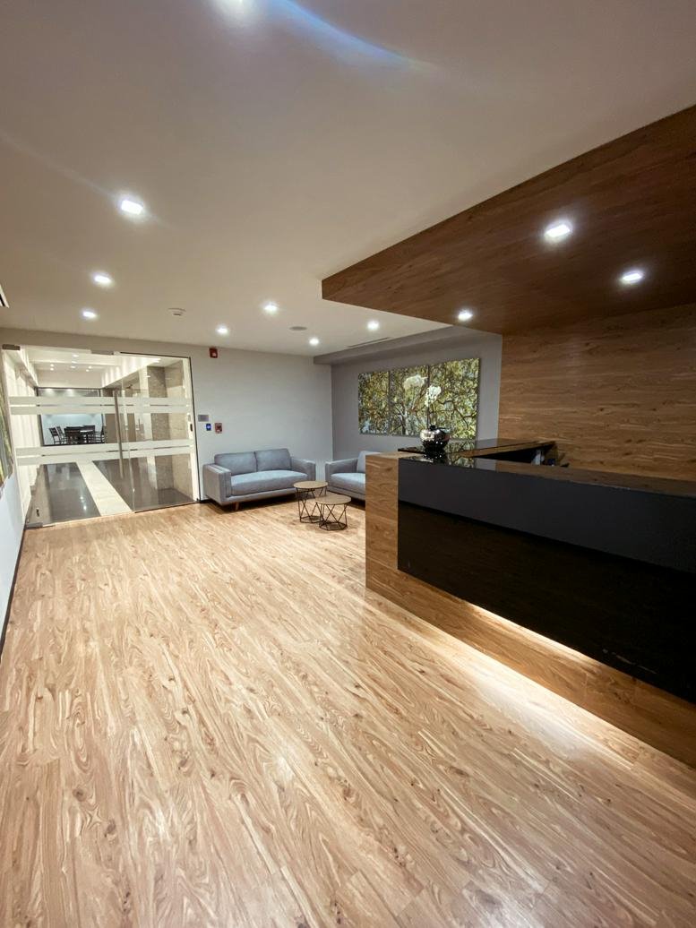 Sleek reception area at Bosques de Ciruelos 186, Pisos 10-A y 12, featuring a black desk and wood paneling.