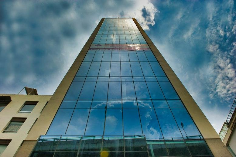 Glass building facade reflecting the sky.