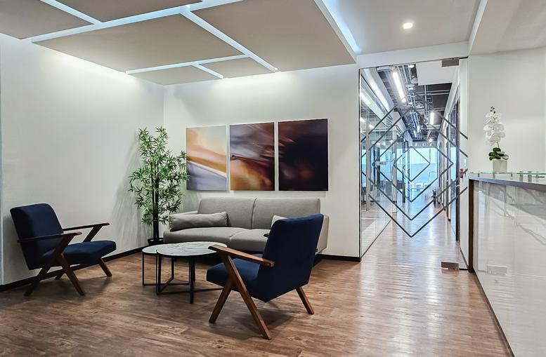 Reception and waiting area with modern blue armchairs and abstract wall art at Torela Corporativo.