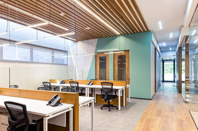 Shared office space with wooden dividers, ergonomic chairs, and teal accent walls.
