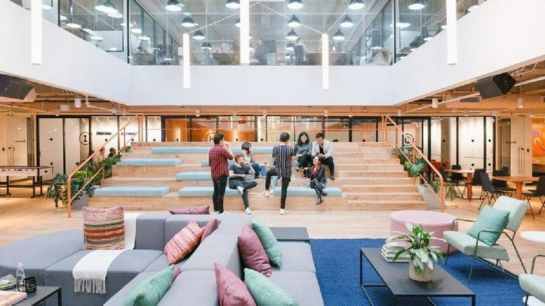 Spacious communal lounge at Calle 26, 92-32, Gold 2 with tiered wooden seating and colorful sofas.