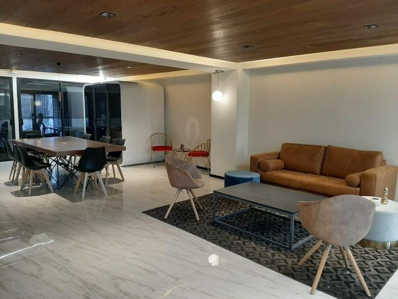 Spacious communal lounge featuring a brown leather sofa and a large wooden dining table.