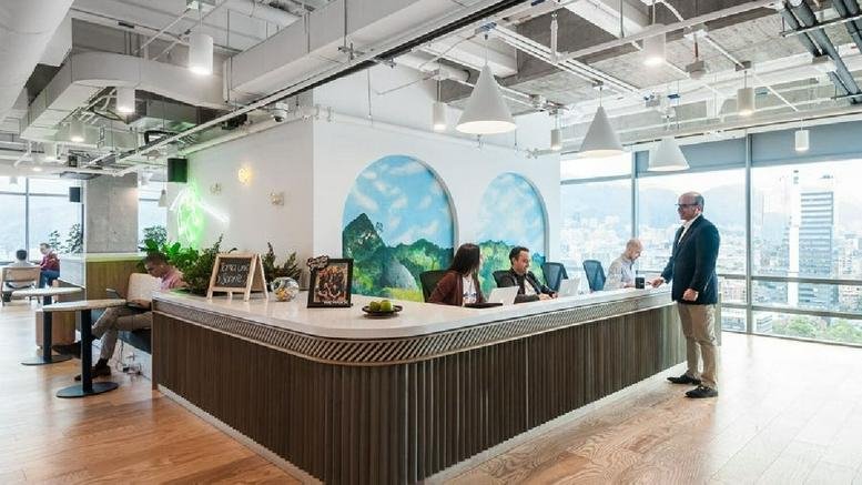 Bright reception desk at Carrera 19 No. 100, 45, Bogotá, Bogota with a wood-slat base and mountain wall murals.