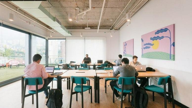 Spacious open-plan workspace at Carrera 42, Sur-145 with colorful art and floor-to-ceiling windows.