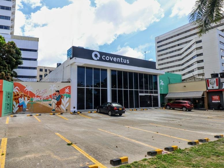 Exterior view of the white facade building at Carrera 60 No. 77-75, Barranquilla with glass windows.