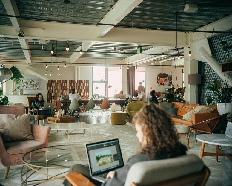 Spacious communal lounge with diverse seating, warm lighting, and greenery at Chophouse Row, Suite 400.