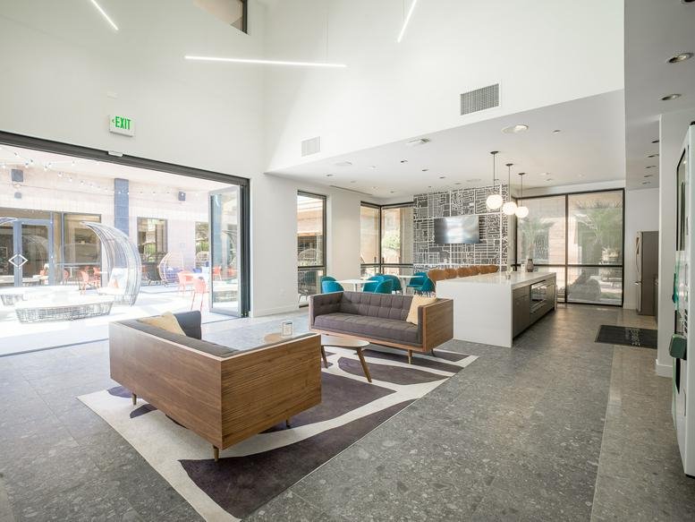 Spacious communal lounge at Cooper Crossing with modern sofas and indoor-outdoor glass wall.