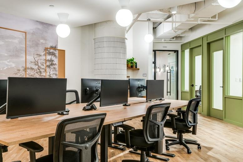 Modern workspace at East Las Colinas Boulevard Suite 300 with desks and green framed walls.