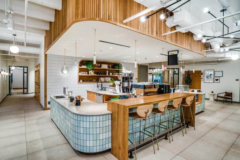 Cafe-style communal area at East Las Colinas Boulevard Suite 300 with a light-wood bar and blue tile accents.