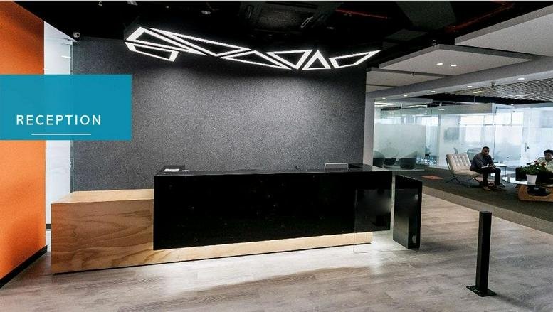 Reception area at the Ecotek Building, Calle 99 con Carrera 11, featuring a geometric light and black desk.