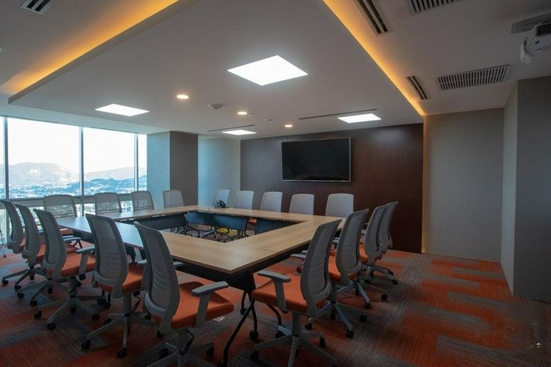Spacious boardroom at Edificio Insigne with a hollow square table and integrated lighting.