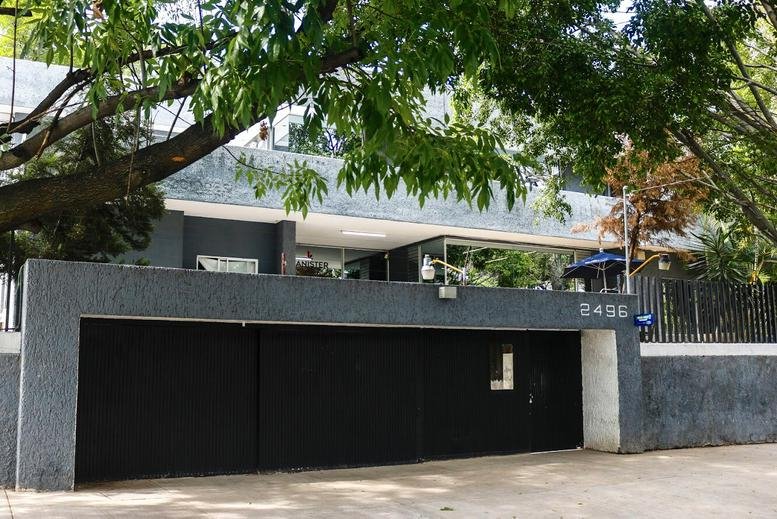 Exterior facade of Efraín Gonzalez Luna No. 2496, Col. Arcos Vallarta, featuring lush trees and a modern gate.