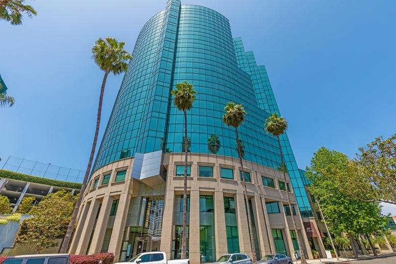 Exterior view of the blue glass curved building at 11400 West Olympic Boulevard Suite 200.