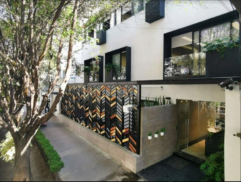 Exterior of the modern white office building at Hipolito Taine Street 244 with a patterned glass gate.
