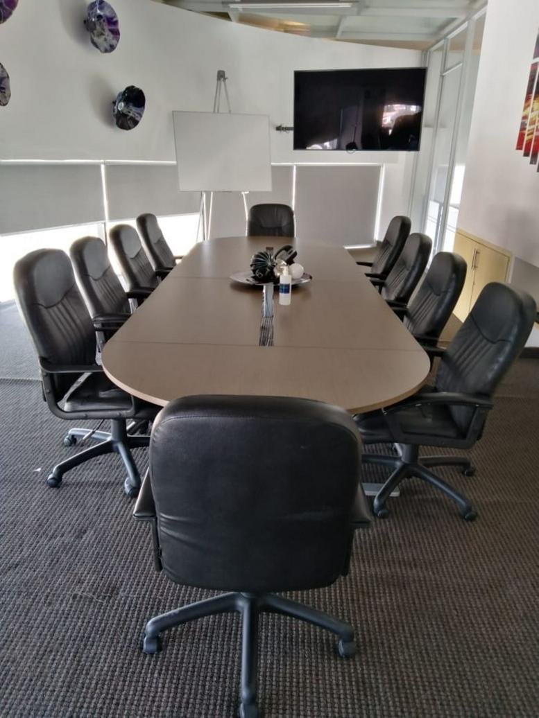 Spacious boardroom featuring a long oval table and black leather chairs.