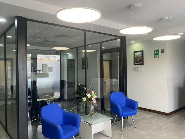 Lounge area with two bright blue armchairs and a glass partition wall looking into a meeting room.