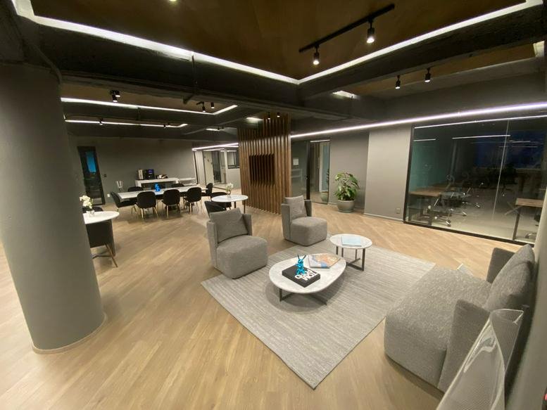 Wide-angle view of a professional lounge and coworking area with wood floors and recessed lighting.