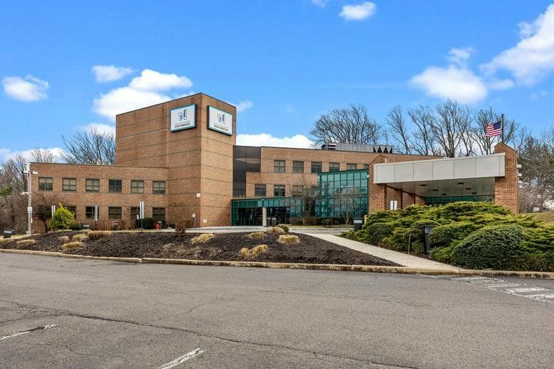 Wide view of the office building exterior under a bright blue sky.