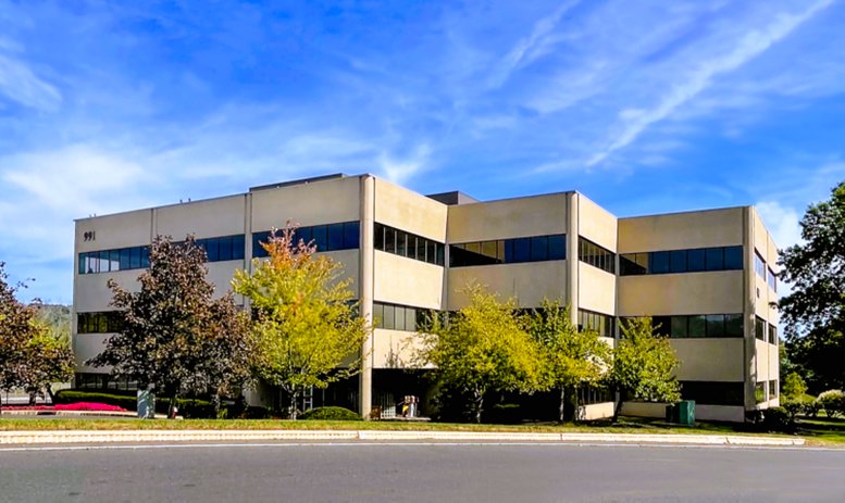 Exterior view of the multi-story beige office building under a blue sky.
