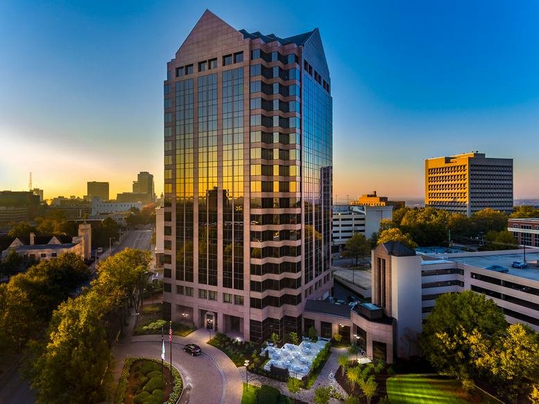 Wide exterior view of the glass-facade tower at 1901 Main Street during sunset.