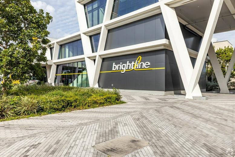 Modern architectural exterior of the building at 1 East Broward Boulevard showing Brightline signage.