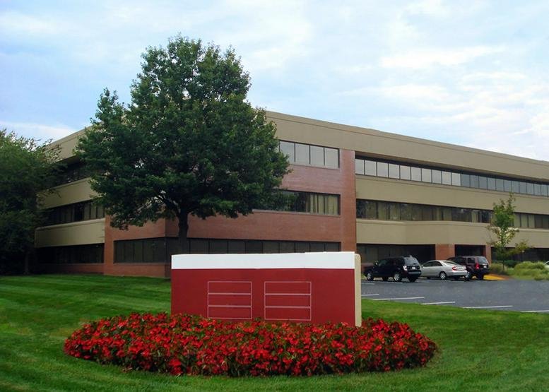 Exterior view of the low-rise 1 Greentree Centre building with red brick accents and manicured lawn.