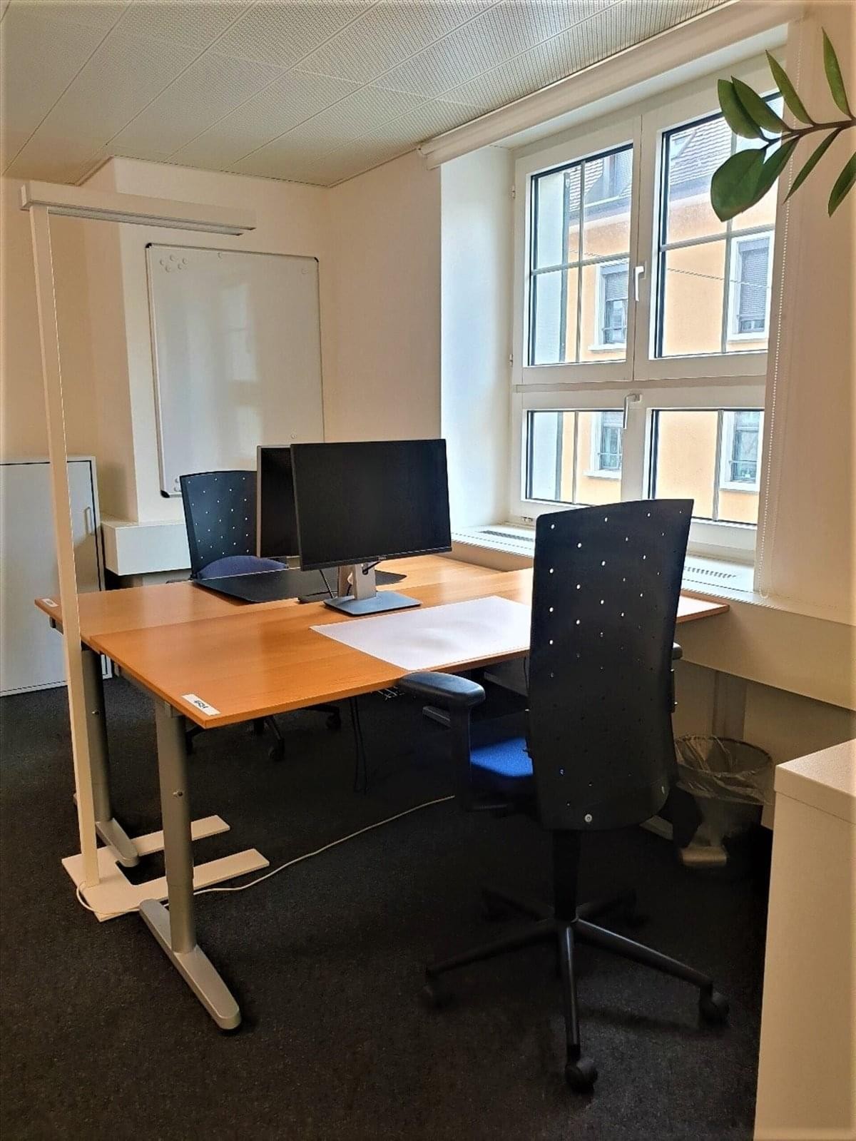 Bright private office with wooden desks and a large window at 1 Rideau Street, Suite 700.