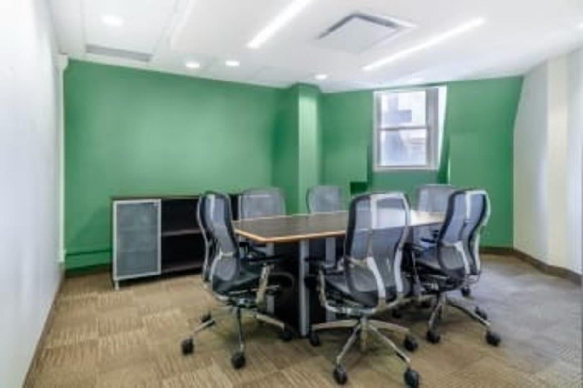 Spacious meeting room at 1 Rideau Street, Suite 700 with a large table, mesh chairs, and green feature walls.