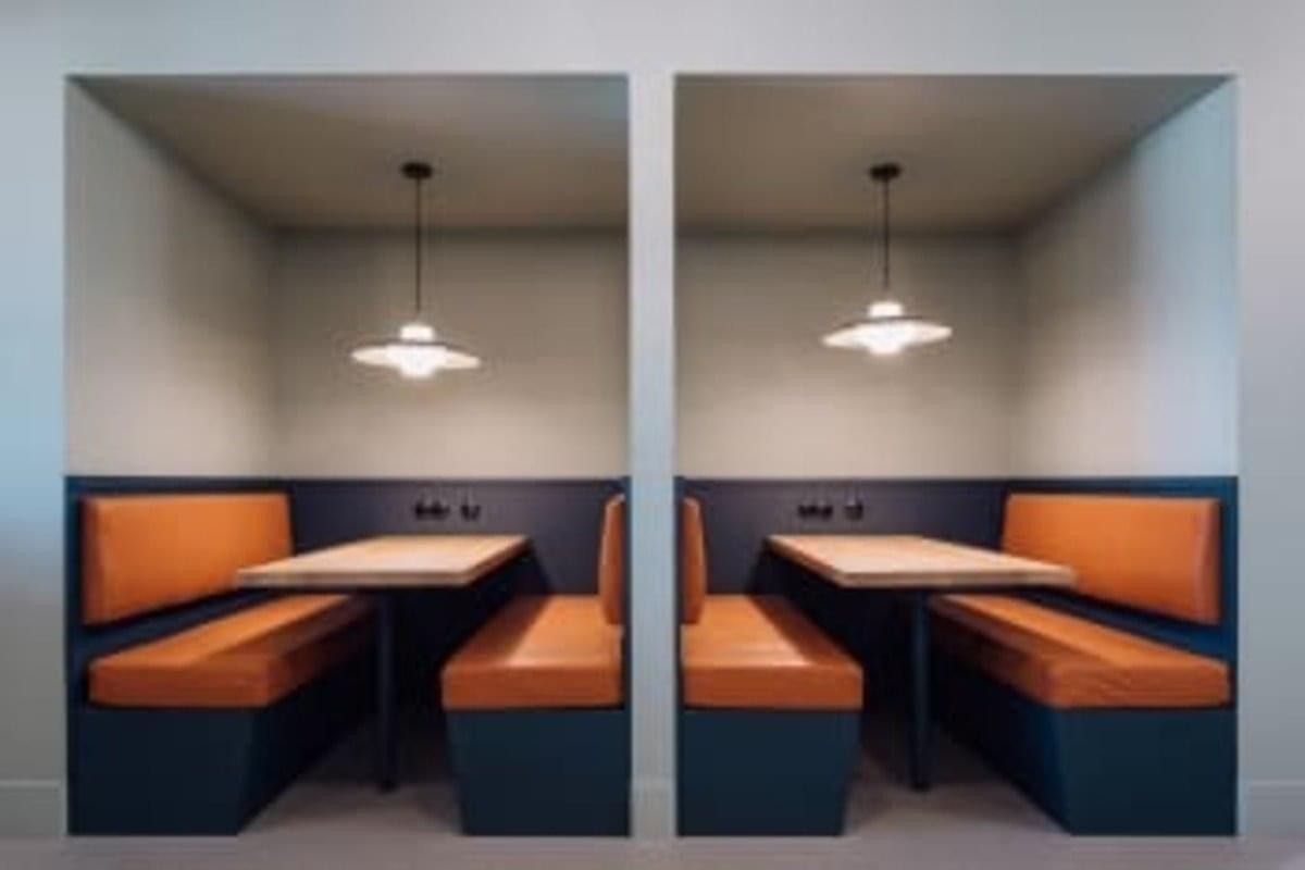 Pair of semi-private dining or meeting booths with orange cushioned seating at 1 Rideau Street, Suite 700.