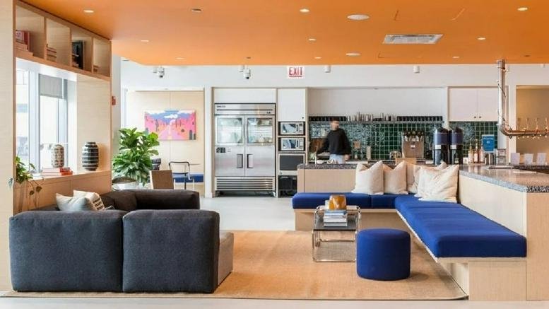 Spacious communal lounge and kitchen area at One South Dearborn with vibrant orange ceiling and blue seating.