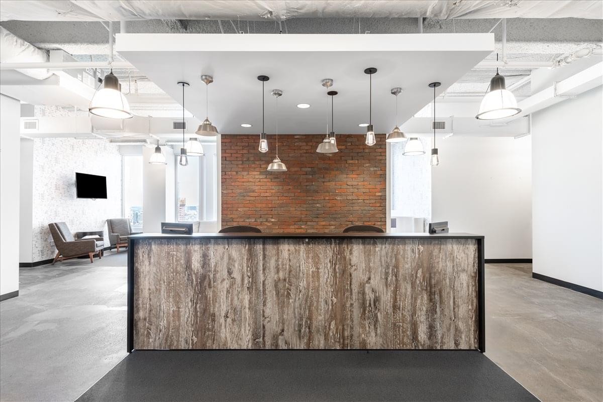 Modern reception desk with wood paneling under a white dropped ceiling at The Leverett Saltonstall Building.