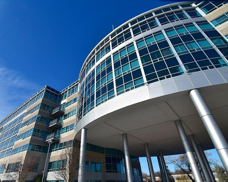 Low-angle exterior view of the modern curved glass facade at 100 Cummings Center.