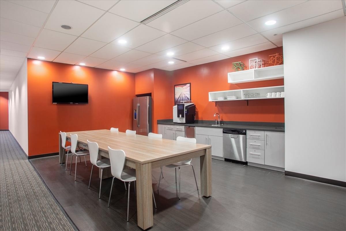 Crosswoods Center, Suite 250 communal kitchen area with an orange feature wall and a long dining table.