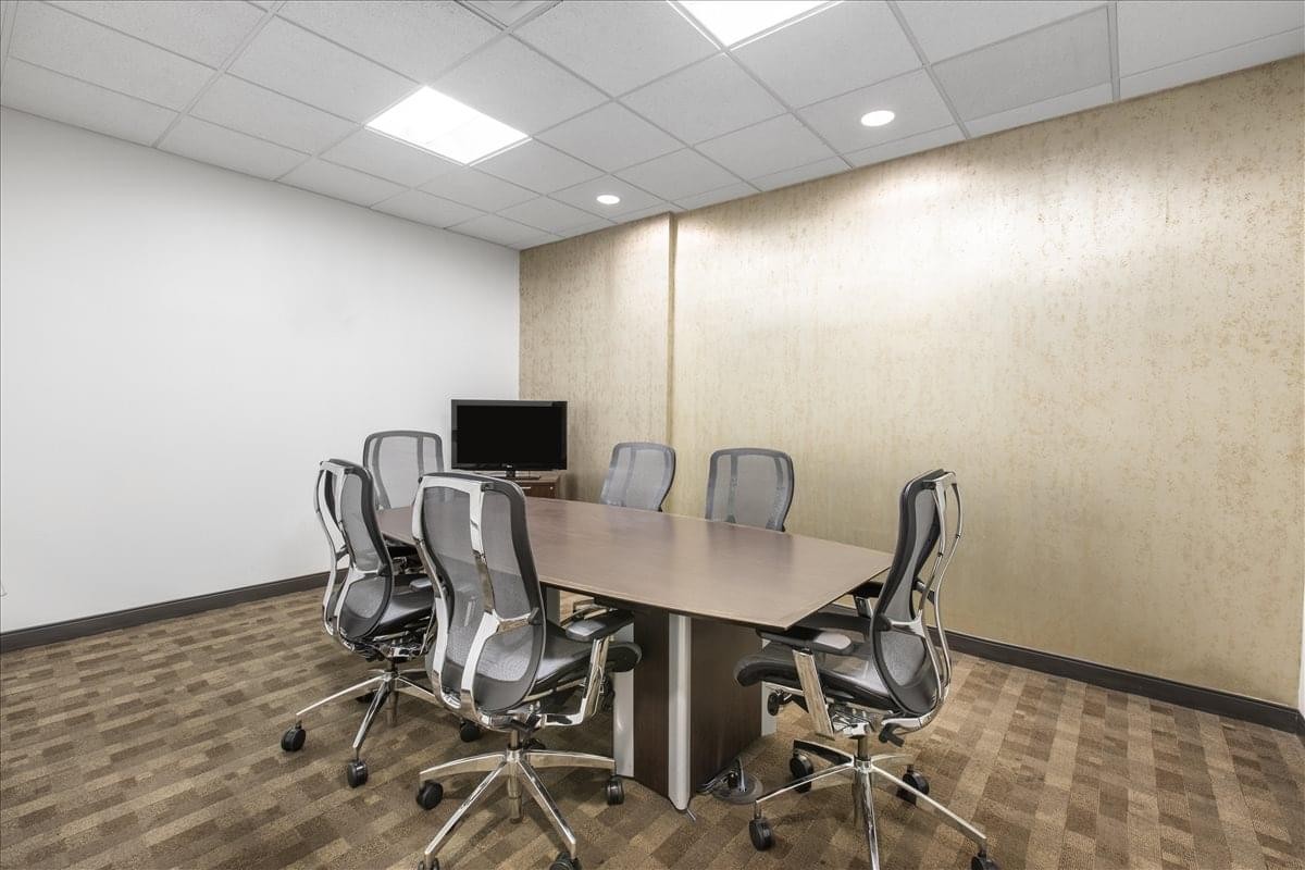 Spacious boardroom with a large rectangular table, mesh chairs, and a feature wall at 100 Park Avenue.