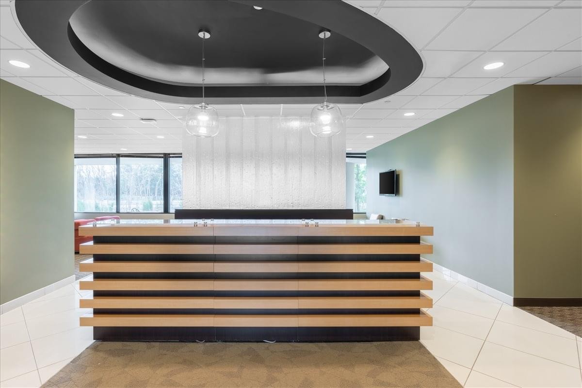Contemporary reception desk at 100 S. Saunders Road featuring horizontal wood slats and a circular ceiling cove.