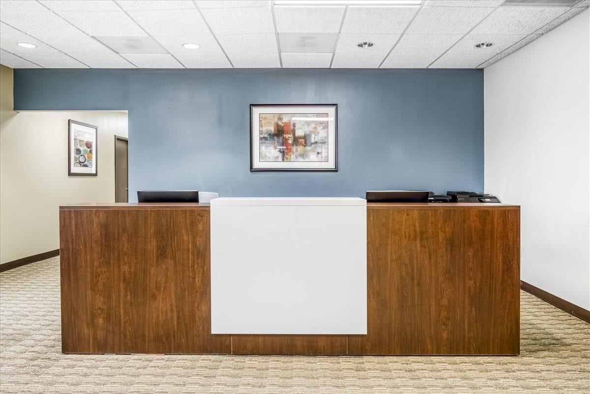 Wood-paneled reception desk in front of a blue feature wall at 100 West Road, Suite 300.