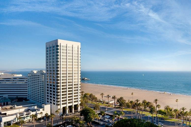 High-angle view of the building exterior next to a sandy beach and the blue Pacific Ocean.