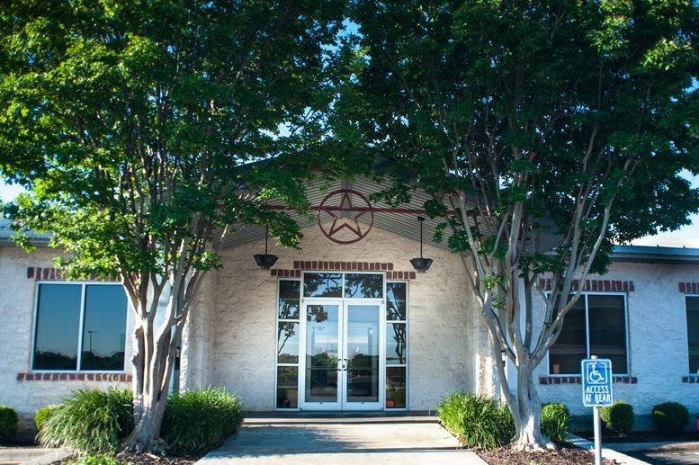 Exterior view of the entrance at 1000 Heritage Center Circle with stone walls and a Texas star emblem.