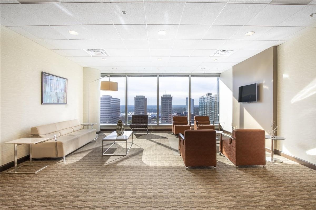 Bright breakout lounge with leather armchairs and floor-to-ceiling city views.