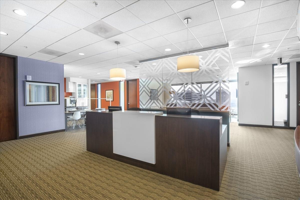 Professional reception area at 1000 Parkwood Circle with a dark wood desk and designer lighting.