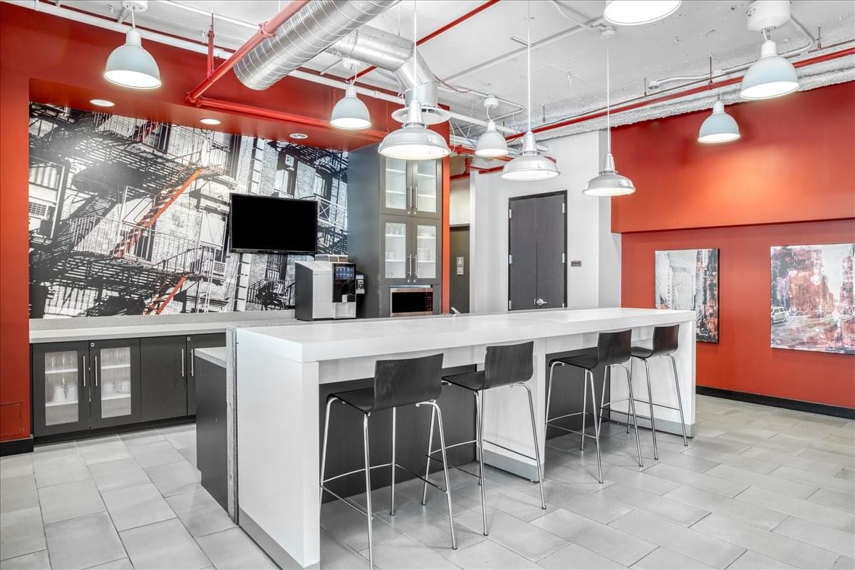 Vibrant communal kitchen and breakout area with red walls and a white marble island.